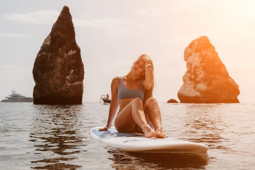 Close up shot of beautiful young caucasian woman with black hair and freckles looking at camera and smiling. Cute woman portrait in a pink bikini posing on a volcanic rock high above the sea