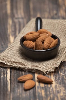 Almonds in a bowl on a wooden background