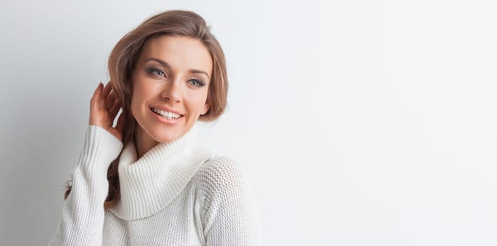 Studio portrait of beautiful long-haired woman in hot sweater on white background