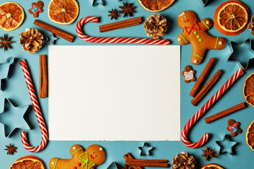 Christmas food frame. Gingerbread cookies, spices and decorations on blue background with blank card for copy space