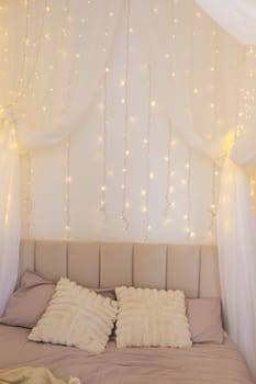 Bedroom in bright colors, decorated for the Christmas holidays. Bed decorated with a garland
