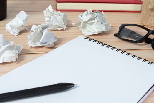 Notepad with trash paper background on wooden desk. Copy space.
