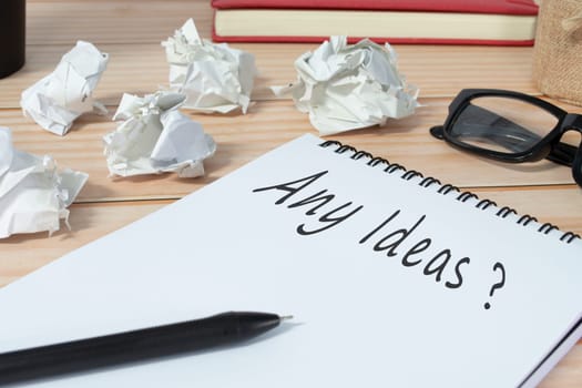Any ideas question written on notepad with trash paper background on office desk. Business concept.