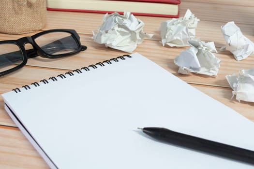 Notepad with trash paper background on wooden desk. Copy space.
