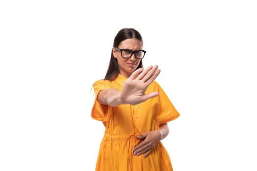 young black-haired woman with glasses dressed in an orange summer dress doubts and is angry.