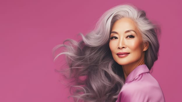 Smiling, elderly, gorgeous Asian woman gray long hair and perfect skin, on a pink background, banner. Advertising of cosmetic products, spa treatments, shampoos and hair care products, dentistry and medicine, perfumes and cosmetology for senior women