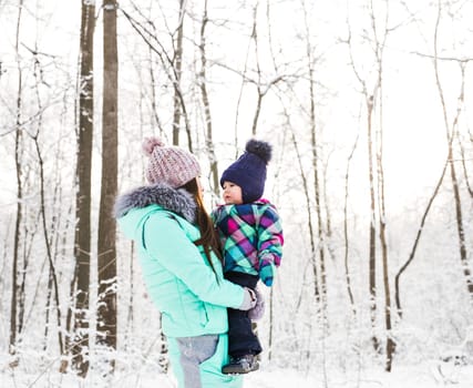 happy family mother and child baby daughter on a winter walk in the woods.