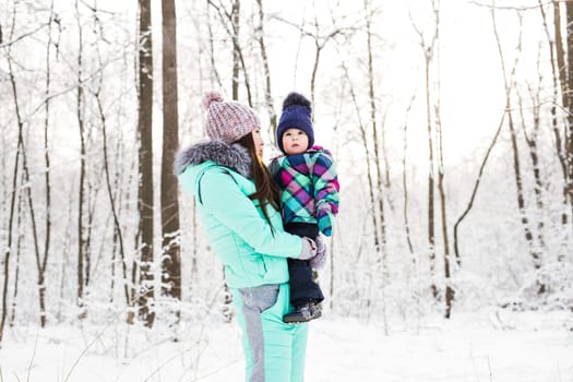 happy family mother and child baby daughter on a winter walk in the woods.