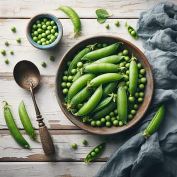 Fresh green peas in bowl with pods and leaves on white wooden table, healthy green vegetable or legume.