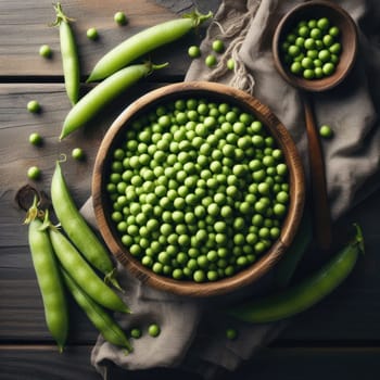 Fresh green peas in bowl with pods and leaves on white wooden table, healthy green vegetable or legume.