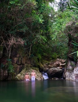 Two unknown people find tranquility in a jungle oasis, surrounded by lush greenery and a babbling creek.