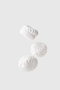 Soaring white zephyr marshmallow on white background. flying food levitation, sweet candy dessert