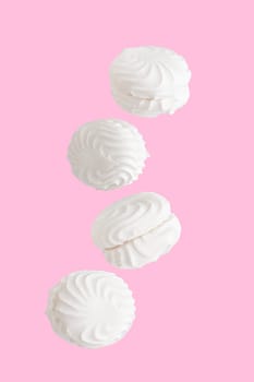 Soaring white zephyr marshmallow on pink background, sweet food levitation