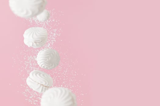 Soaring white zephyr marshmallow on pink background with sugar powder, levitation banner with copy space