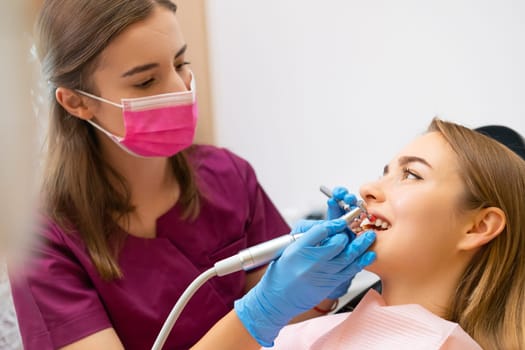 Dentist doing a dental treatment on a woman for perfect smile.