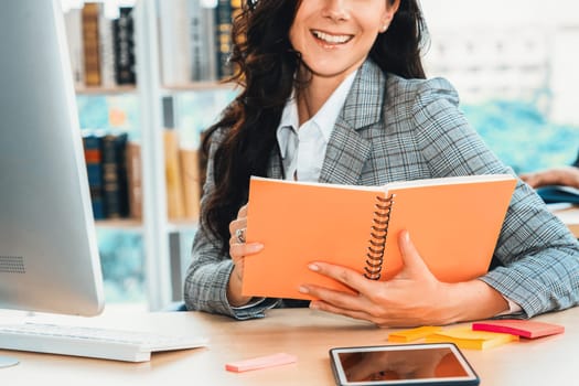 Business woman reads book at office desk close up view . Jivy