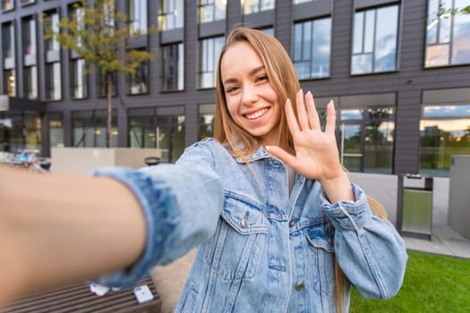 Attractive young female tourist with long blond hair taking a selfie in the street.