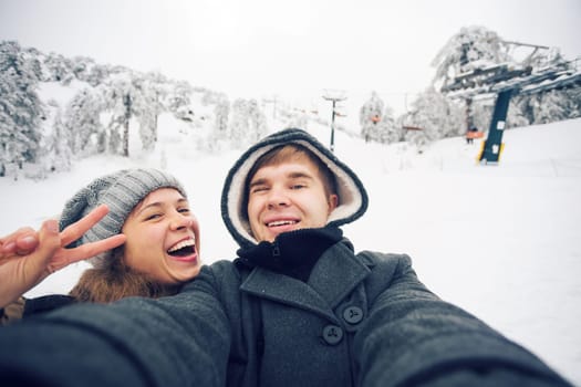 people, season, love, technology and leisure concept - happy couple taking selfie by smartphone over winter background.