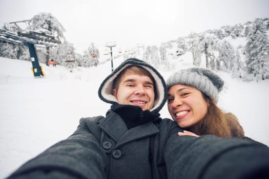 Happy boyfriend and girlfriend making selfie on a winter nature.