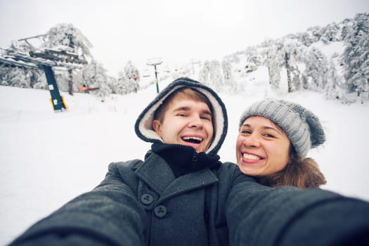 Young man and woman taking a selfie in winter using smart phone