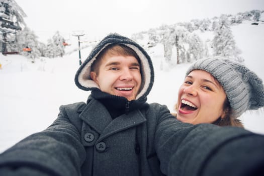 people, season, love, technology and leisure concept - happy couple taking selfie by smartphone over winter background.