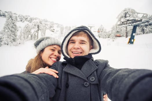 Happy boyfriend and girlfriend making selfie on a winter nature.