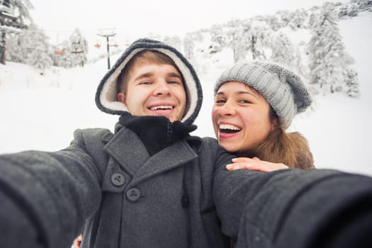 people, season, love, technology and leisure concept - happy couple taking selfie by smartphone over winter background.