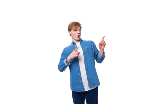 portrait of a european red-haired student guy dressed in a blue denim shirt on a white studio background.