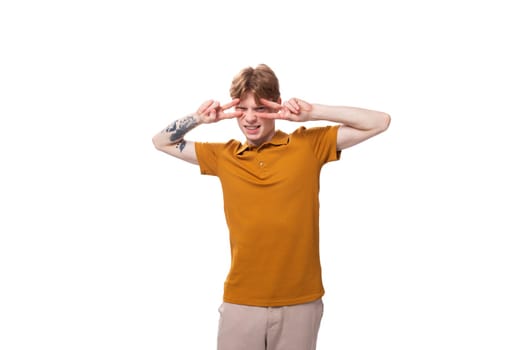 portrait of a young adorable redhead man dressed in a yellow t-shirt on a white background with copy space.