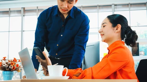 Two business people talk project strategy at office meeting room. Businessman discuss project planning with colleague at modern workplace while having conversation and advice on financial report. Jivy