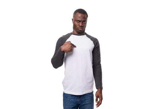 young well-groomed African guy dressed in a black-and-white sweatshirt and jeans in the studio on a white background with copy space.