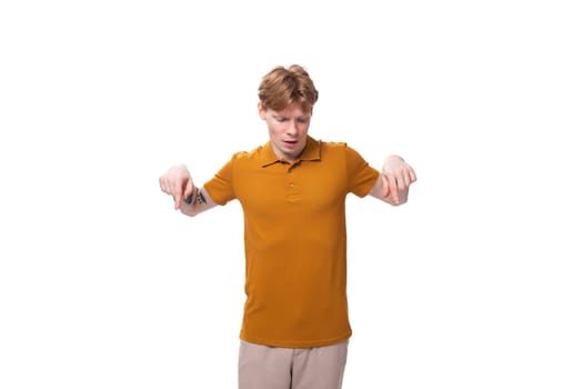 young caucasian man with red hair is dressed in a yellow t-shirt on a studio background.