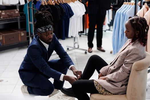 African american worker helping client with stylish shoes, woman shopping for formal wear in showroom. Fashionable customer buying fashion collection in boutique shop. Fashion concept