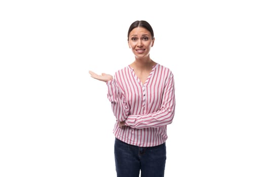 young smart caucasian woman with black hair gathered in a ponytail dressed in a striped blouse stands thoughtfully.