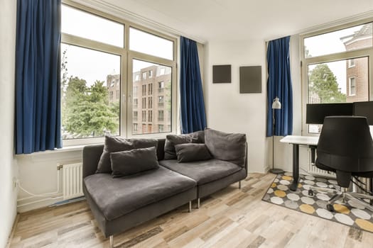 a living room with wood flooring and blue drapes hanging on the windows in the room is very spacious