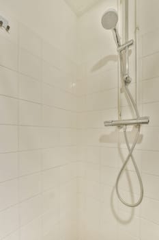 a shower with white tiles on the walls and floor, as seen from the bottom down to the top right corner
