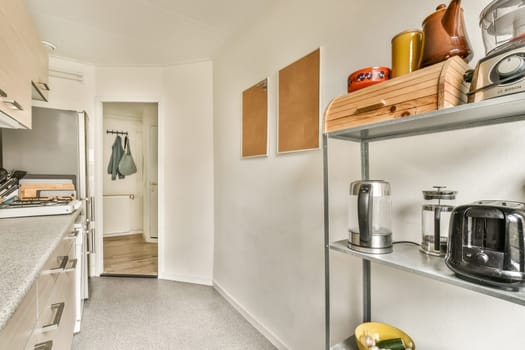 a kitchen area with some appliances on the counter tops and shelves in the wall to the right is an open door