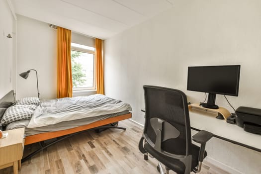 a bedroom with a bed, desk and computer monitor on the wall in front of the window that looks out to the trees outside