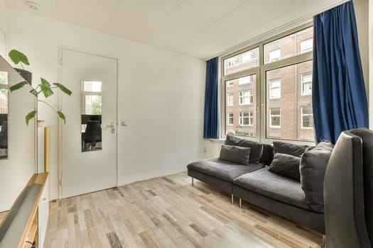 a living room with wood flooring and blue drapes on the window in the photo is taken from outside