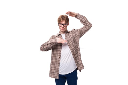 a young handsome red-haired guy in a plaid shirt is actively gesturing against the background with copy space.