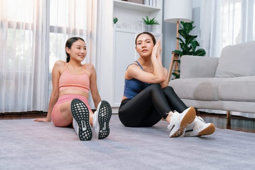 Asian woman in sportswear with her trainer or workout buddy, smiling and posing cheerful gesture. Home workout training or exercise fitness lifestyle in pursuit of healthy lifestyle. Vigorous