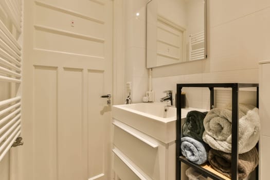 a bathroom with white walls and wood flooring, there is a towel rack on the wall next to the sink