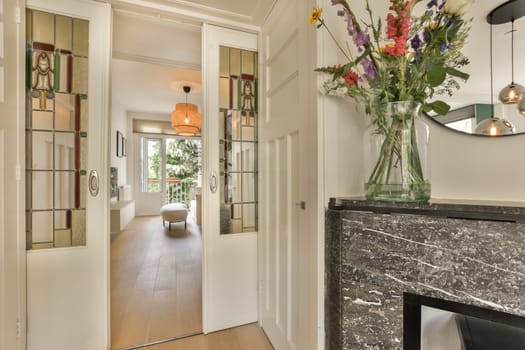 some flowers in a vase on the wall next to a fire place with mirror doors and white trim around it