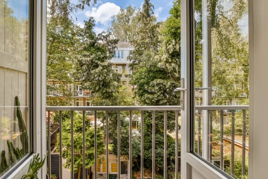 an outside area with trees and buildings in the background, taken from inside a window looking out onto a balcony