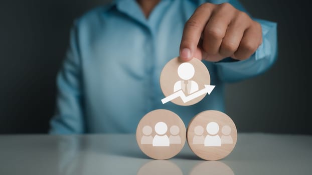 Concept Business and HR for leaders and team leaders. A person selects a manager icon printed on a circular wooden plaque.