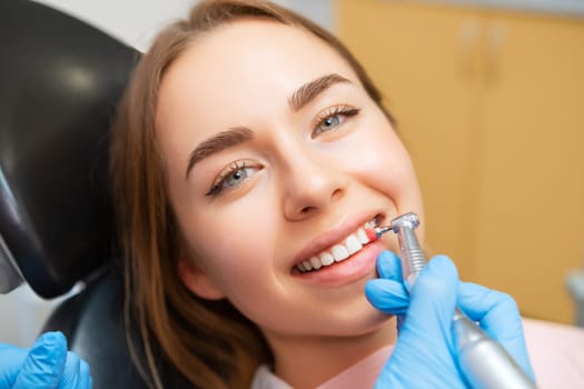 Dentist doing procedure of teeth grinding to beautiful woman in dental clinic.