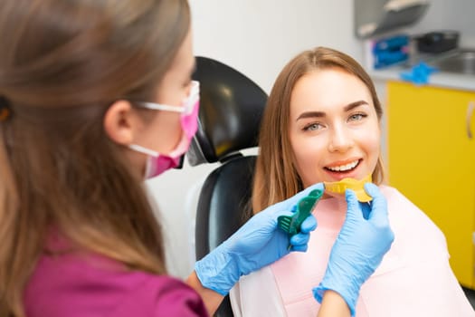Dentist in rubber gloves holding a spoon for dental impressions for making alignments.