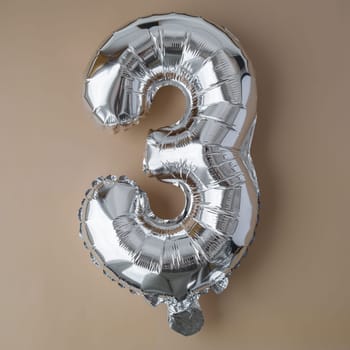 3 three metallic balloon on beige neutral background. Greeting card silver foil balloon number Happy birthday holiday concept. Copy space for text. Celebration party congratulation decoration