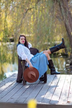 Autumn lake woman. She sits by a pond on a wooden pier in autumn and admires nature. The concept of tourism, weekends outside the city