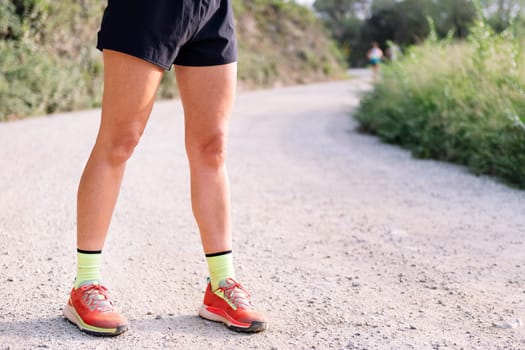 fitness legs of an unrecognizable sportswoman in the countryside, concept of sport in nature and active lifestyle, copy space for text